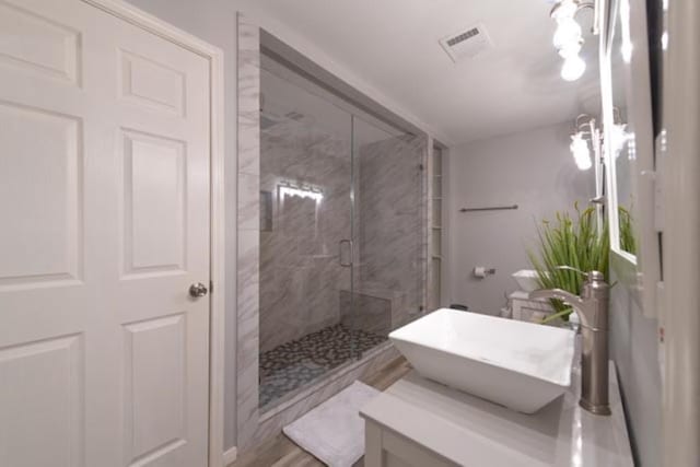 full bath featuring vanity, a marble finish shower, and visible vents