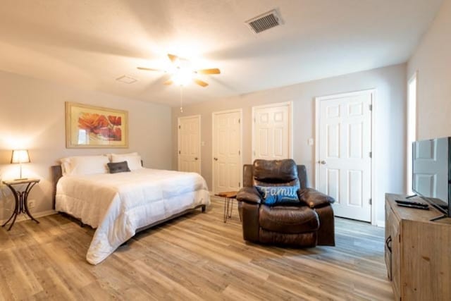 bedroom featuring a ceiling fan, two closets, visible vents, and light wood-style floors