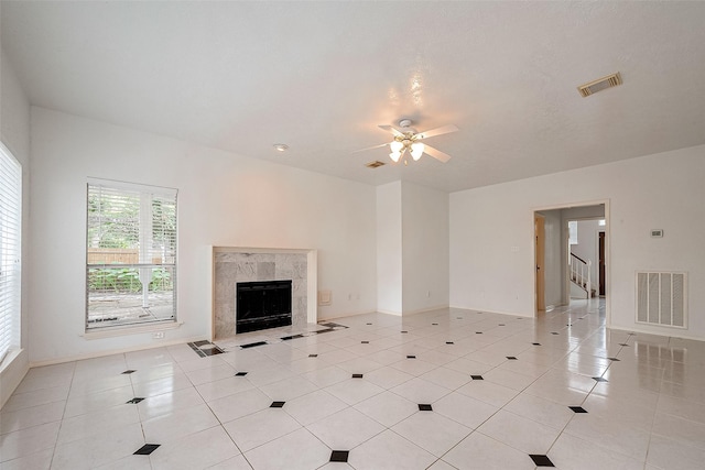 unfurnished living room featuring ceiling fan, a fireplace, and light tile patterned floors