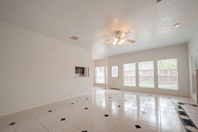 tiled empty room with a textured ceiling and ceiling fan