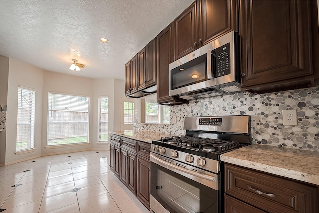 kitchen featuring appliances with stainless steel finishes, dark brown cabinets, a textured ceiling, and light tile patterned floors