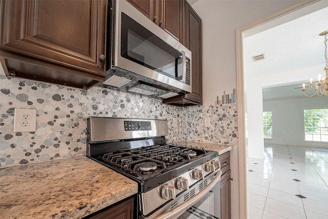 kitchen featuring a chandelier, stainless steel appliances, light stone countertops, decorative light fixtures, and backsplash