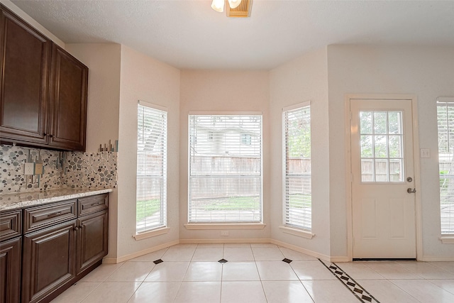 doorway with light tile patterned flooring and plenty of natural light