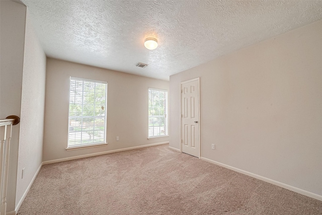 carpeted empty room with a textured ceiling