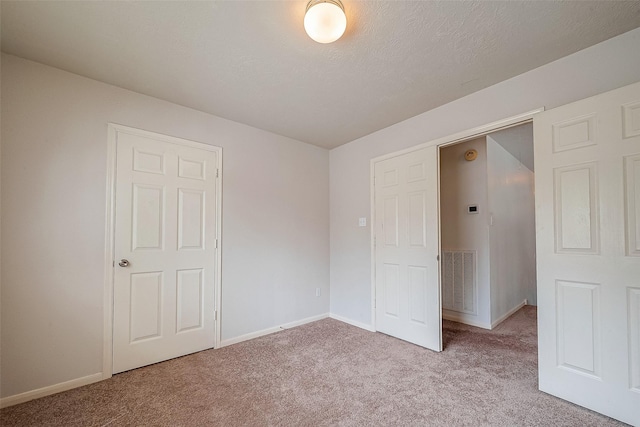 unfurnished bedroom with a textured ceiling and light carpet