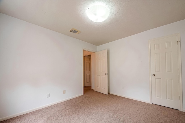 carpeted empty room featuring a textured ceiling