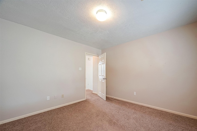 empty room with light colored carpet and a textured ceiling