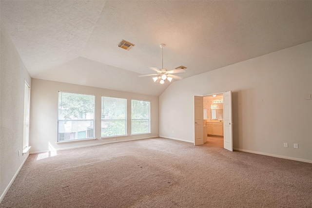 empty room with ceiling fan, vaulted ceiling, a textured ceiling, and carpet flooring