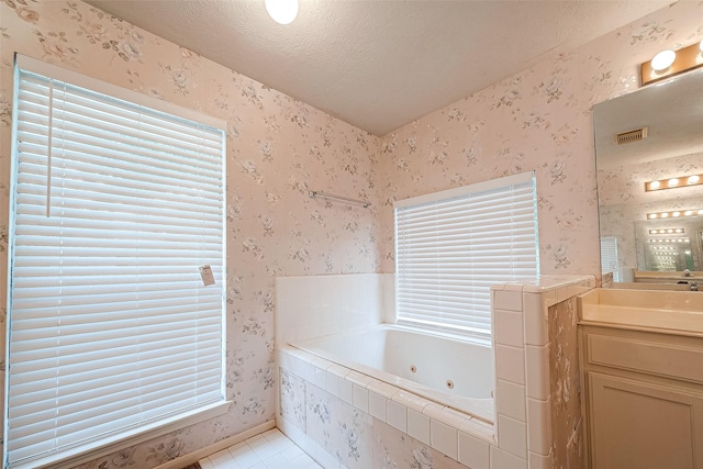 bathroom featuring a textured ceiling, tile patterned floors, tiled bath, and vanity