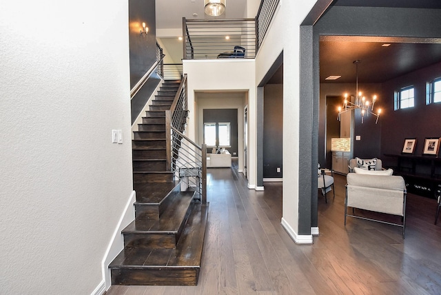 foyer featuring a high ceiling, dark wood-type flooring, an inviting chandelier, and a wealth of natural light