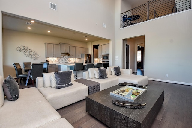 living room featuring a high ceiling and dark hardwood / wood-style flooring