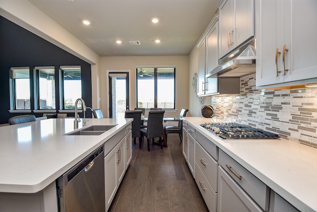 kitchen with dark hardwood / wood-style floors, stainless steel appliances, decorative backsplash, a kitchen island with sink, and sink