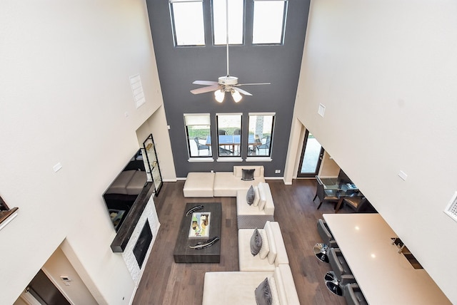 living room with ceiling fan, dark hardwood / wood-style flooring, and a towering ceiling