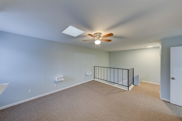 carpeted empty room with a skylight and ceiling fan