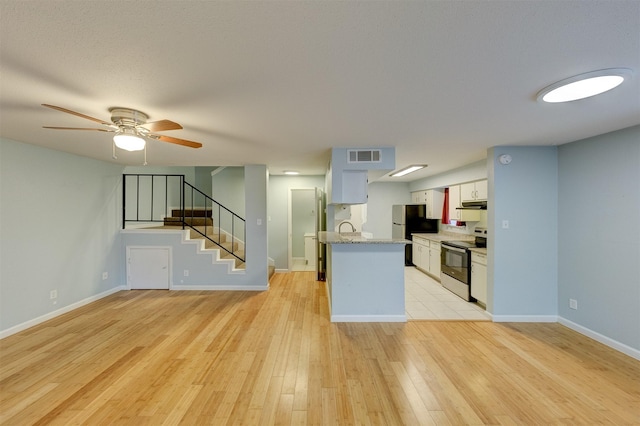 kitchen with ceiling fan, stainless steel appliances, white cabinetry, and light hardwood / wood-style flooring