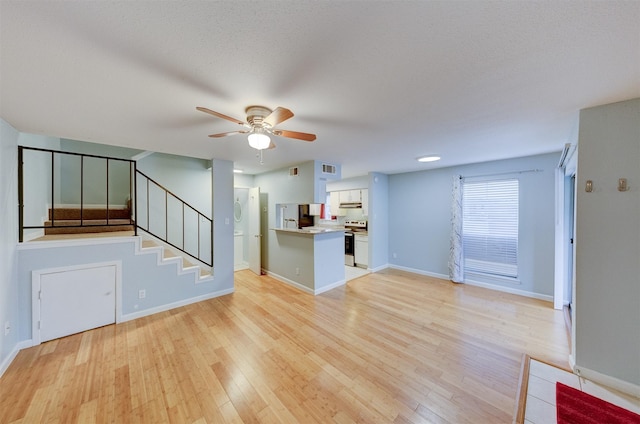 unfurnished living room featuring ceiling fan, light wood-type flooring, and a textured ceiling