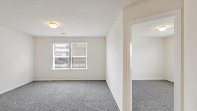 spare room featuring a textured ceiling and carpet