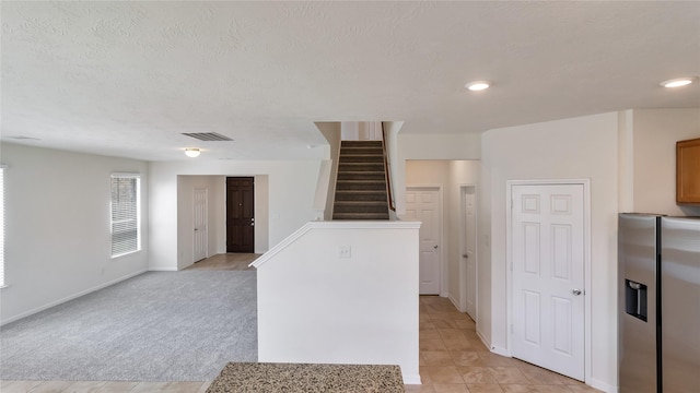 kitchen featuring light colored carpet, stainless steel fridge with ice dispenser, a textured ceiling, and a center island