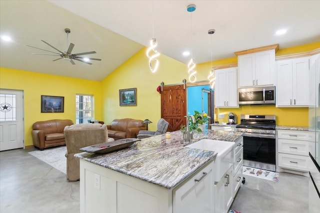 kitchen with stainless steel appliances, white cabinets, a kitchen island with sink, and a barn door