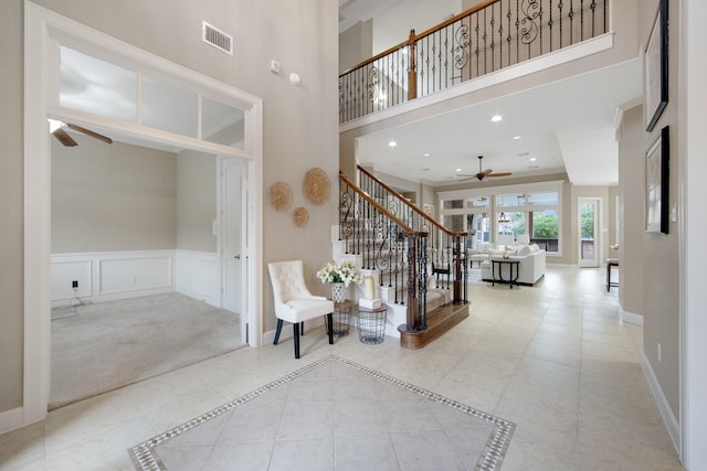 entryway featuring ceiling fan, light tile patterned floors, and a towering ceiling