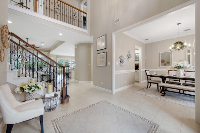 tiled foyer with crown molding and an inviting chandelier