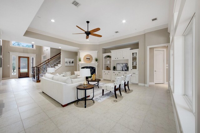 living room with ceiling fan, light tile patterned floors, crown molding, and built in features