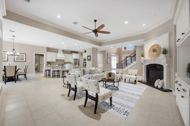 tiled living room featuring ceiling fan with notable chandelier, sink, and crown molding