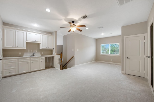 kitchen with light carpet, white cabinetry, and sink