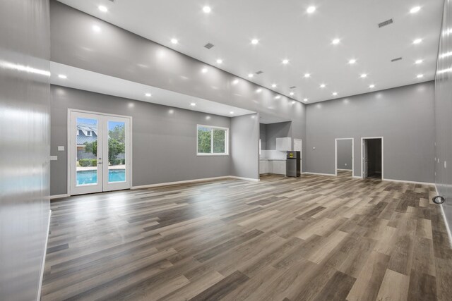 unfurnished living room featuring a high ceiling, wood-type flooring, and french doors