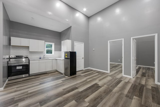 kitchen featuring sink, white cabinetry, appliances with stainless steel finishes, and a towering ceiling