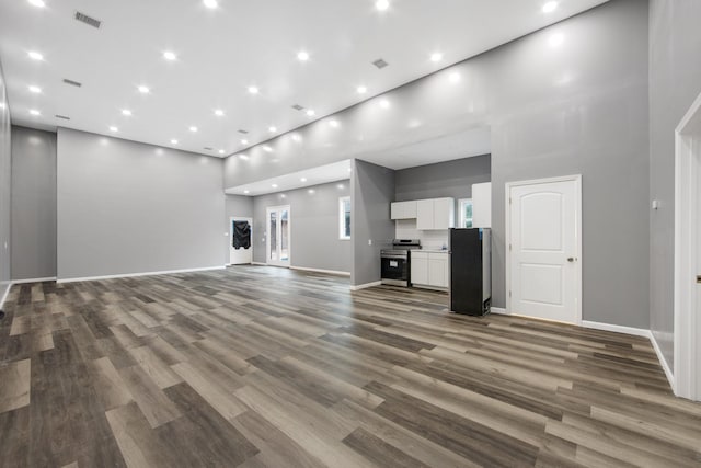 unfurnished living room with a high ceiling, plenty of natural light, and hardwood / wood-style flooring