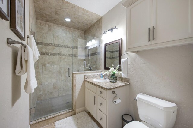 bathroom featuring a shower with door, toilet, and vanity