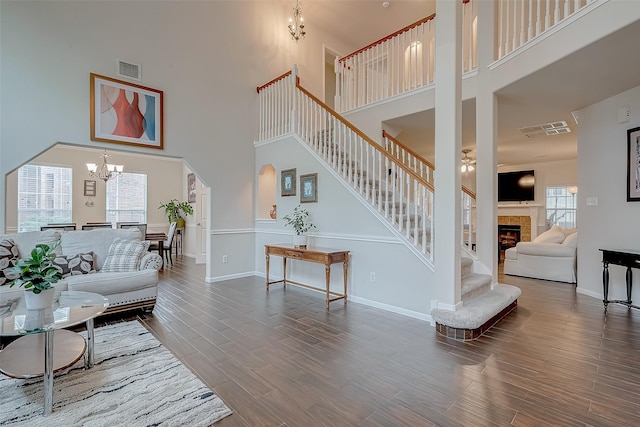 living room featuring a tiled fireplace, a notable chandelier, and a high ceiling