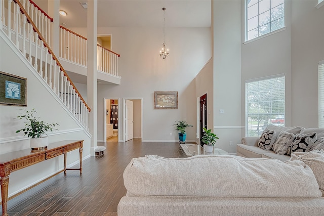 living room with dark wood-type flooring, an inviting chandelier, and a towering ceiling