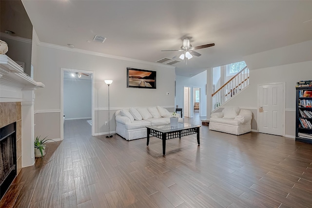 living room featuring ornamental molding, a tiled fireplace, and ceiling fan