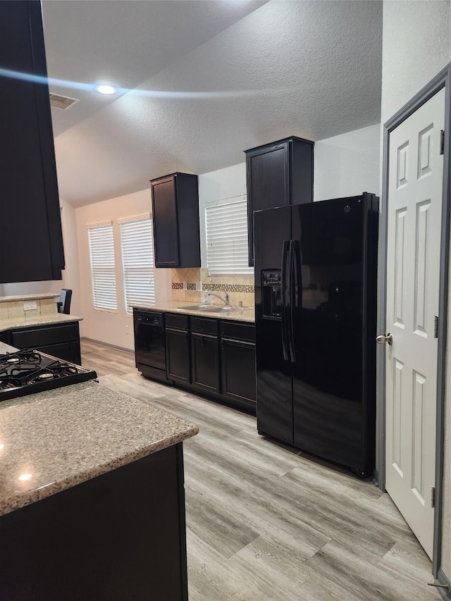 kitchen featuring decorative backsplash, light hardwood / wood-style flooring, and black appliances