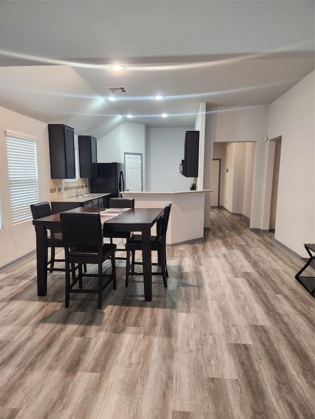 dining space featuring vaulted ceiling and light wood-type flooring