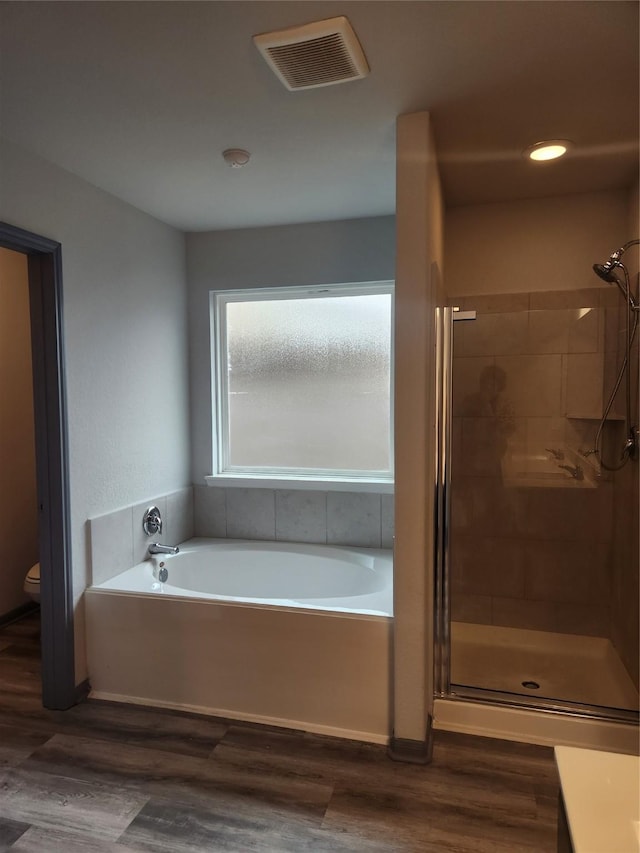 bathroom with hardwood / wood-style flooring, toilet, and independent shower and bath