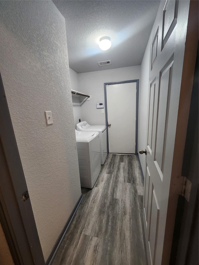 laundry area with independent washer and dryer, dark hardwood / wood-style floors, and a textured ceiling