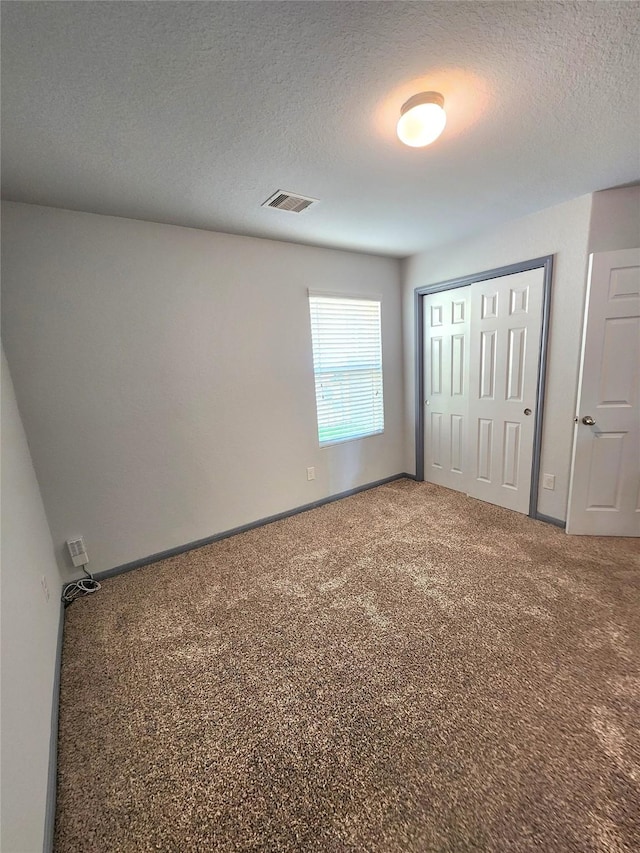 unfurnished bedroom featuring a closet, carpet floors, and a textured ceiling