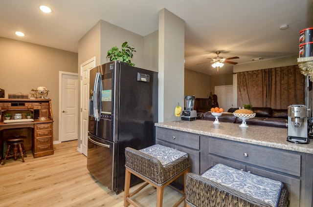 kitchen with stainless steel refrigerator, light stone countertops, light wood-type flooring, and ceiling fan