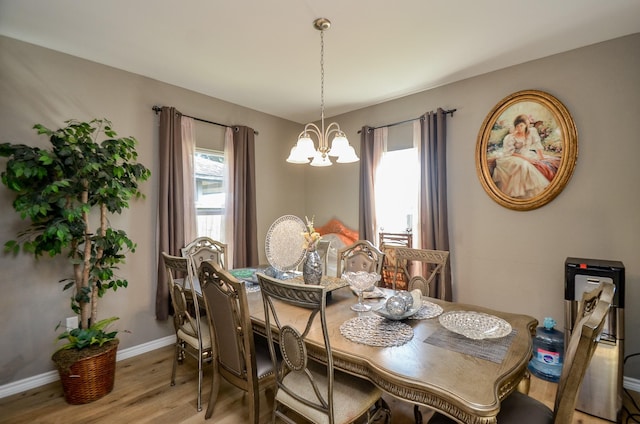 dining area with a healthy amount of sunlight, light wood-type flooring, and an inviting chandelier