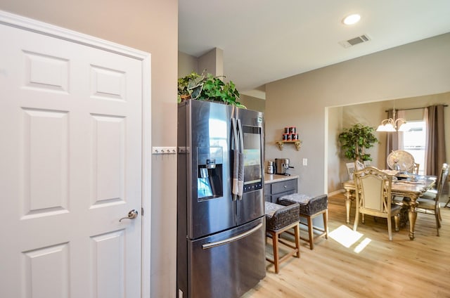 kitchen with stainless steel fridge, light wood-type flooring, and an inviting chandelier