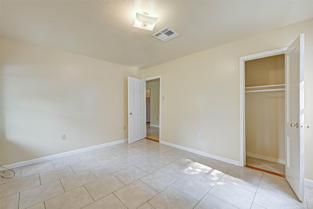 unfurnished bedroom featuring a textured ceiling, a closet, and light tile patterned floors