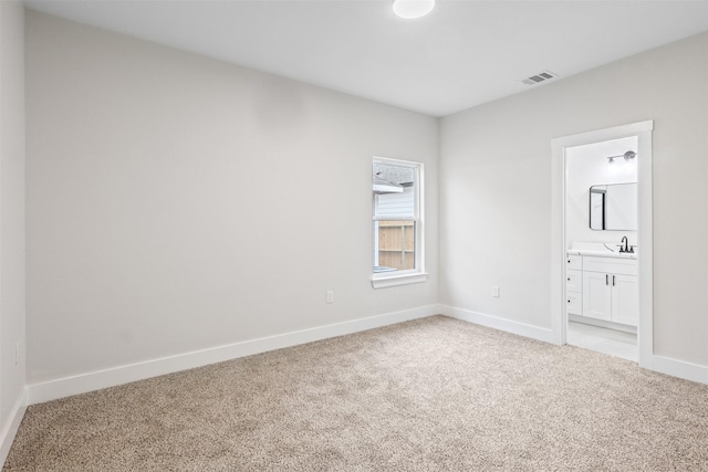 unfurnished bedroom with sink, ensuite bath, and light carpet