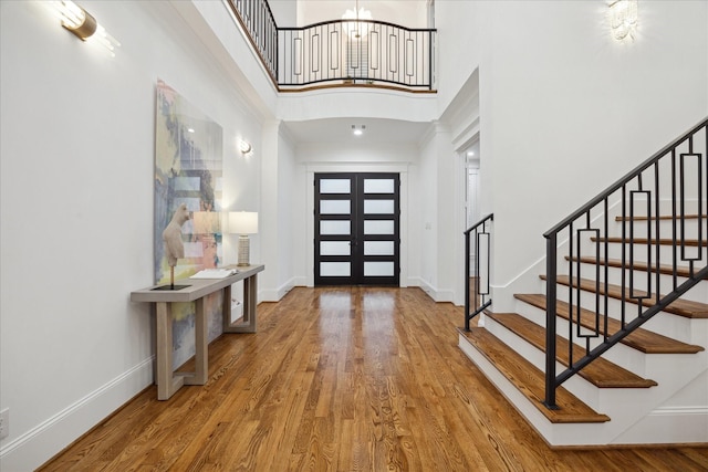 entrance foyer featuring a towering ceiling, french doors, and hardwood / wood-style floors