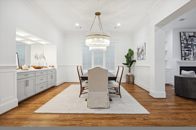 dining space with ornamental molding, light hardwood / wood-style floors, and a notable chandelier