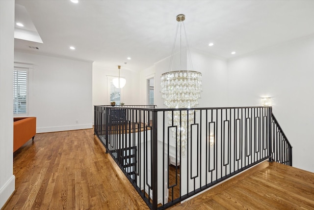 hallway with hardwood / wood-style floors, an inviting chandelier, and crown molding