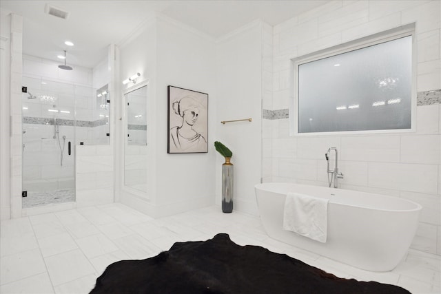 bathroom featuring independent shower and bath, ornamental molding, and tile walls