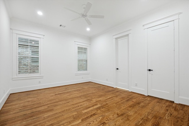 empty room featuring plenty of natural light, ceiling fan, ornamental molding, and hardwood / wood-style floors